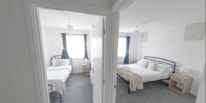 a white bedroom with two beds and a window at Sleeps 5 - Private Garden- Free Parking in Corby