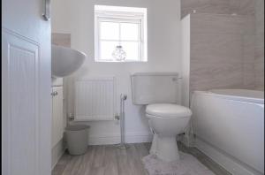 a white bathroom with a toilet and a sink at Sleeps 5 - Private Garden- Free Parking in Corby