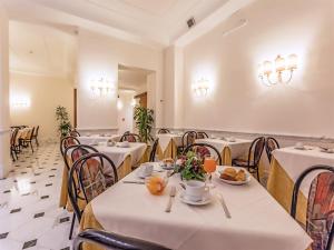 uma sala de jantar com mesas e cadeiras brancas em Raeli Hotel Noto em Roma