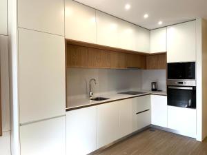 a kitchen with white cabinets and a sink at Vila do Conde - Os Maias in Vila do Conde