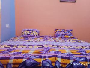 a bedroom with a bed with purple and yellow comforter at Swastik HomeStay in Ayodhya