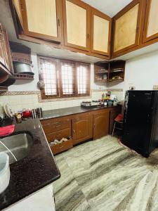 a kitchen with wooden cabinets and a black refrigerator at Bacadi Inn Holiday Apartment in Cochin +5 photos