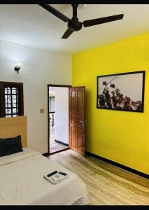a bedroom with a bed and a yellow wall at Bacadi Inn Holiday Apartment in Cochin