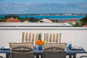 a table with two chairs and oranges on a balcony at Apartment Lipotica 1 in Nin