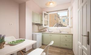 a kitchen with green cabinets and a table and a window at Pension Omorfi Poli in Nafplio