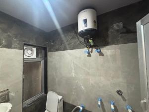 a bathroom with a toilet and a shower with a tank at Yuvraj Guest house in Khātu