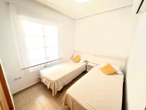 a room with two beds and a window at Adosado Mar Serena in San Juan de los Terreros