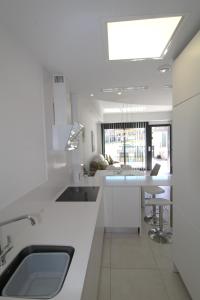 een witte keuken met een wastafel en een tafel bij Fabulous Villa with private pool & large roof solarium in Villamartin