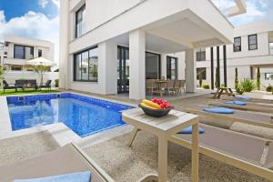 een huis met een zwembad en een fruitschaal op een tafel bij Villa Amity in Protaras