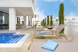 een patio met ligstoelen en een zwembad bij Villa Amity in Protaras