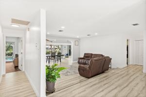 a living room with a leather chair and a dining room at Gulf Breeze Haven Direct Gulf Access Pool+Dock in Cape Coral
