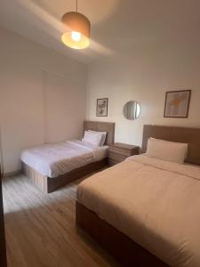 une chambre d'hôtel avec deux lits et une lampe dans l'établissement Privado by Manazil, 12 First Guest! Stylish Lakeview 2BR, au Caire