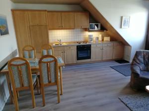 a kitchen with wooden cabinets and a table and chairs at Ferienwohnung Gartenblick mit Balkon in Maasholm