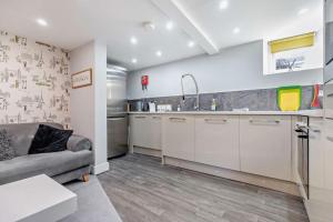 a kitchen with white cabinets and a couch in a room at Garden Mews - 2 double bedrooms - Harrogate Holiday Apartments in Harrogate +4 photos
