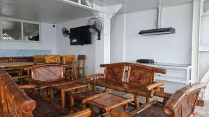 a room with wooden tables and chairs and a television at Lydias House kaputian samal in Kaputian