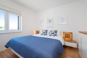 a white bedroom with a blue bed and two pillows at Apartment Lipotica 1 in Nin