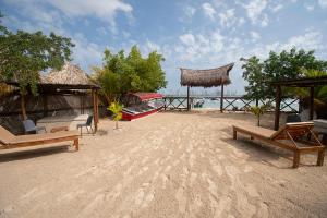 巴鲁岛AMALIFE Beach Club & Hotel的沙滩上沙滩上摆放着椅子和一条船 更多37张照片