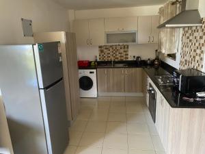 a kitchen with a refrigerator and a washer and dryer at Westpointe 2 bedroom master ensuite comfy home in Nairobi