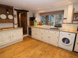 a kitchen with a sink and a washing machine at Glandwr Cottage in Llanbedr