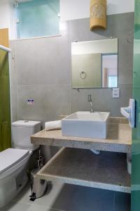 ein Badezimmer mit Waschbecken, Toilette und Spiegel in der Unterkunft Residencial Falésias de Pitinga in Arraial d'Ajuda + 33 Fotos