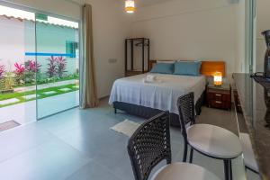 ein Schlafzimmer mit einem Bett und einem Tisch und Stühlen in der Unterkunft Residencial Falésias de Pitinga in Arraial d'Ajuda