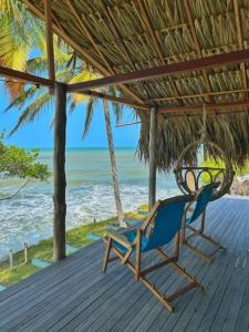 un'amaca e una sedia su un portico con la spiaggia di Entre Palmas Cabañas a Moñitos