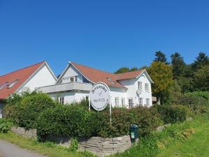 een wit huis met een klok ervoor bij Feriestedet Skovly in Klemensker