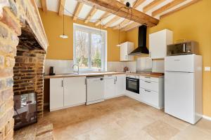 una cucina con elettrodomestici bianchi e un muro di mattoni di Le Logis de Saint Michel de Livet - 5 chambres a Livarot