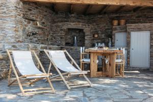 two folding chairs and a wooden table on a patio at Amoni Andros in Agia Eleousa