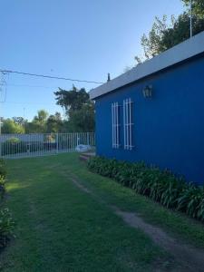 ein blaues Gebäude neben einem Hof mit Pflanzen in der Unterkunft Casa Quinta Arroyo del Medio in Acindar