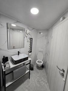a white bathroom with a sink and a toilet at Apartmani Meglić in Barbat na Rabu
