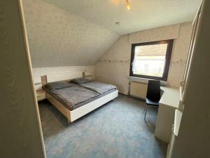 a bedroom with a bed and a desk and a window at Ferienwohnung Ludwig in Karlstadt