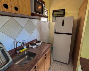 a small kitchen with a sink and a refrigerator at Vilamar Suítes in Aquiraz