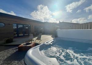 a hot tub sitting on a patio with two chairs at The Tin Shed in Rhayader