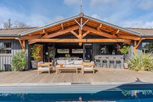 a wooden pavilion with a pool in front of a house at VillaCanau in Lacanau