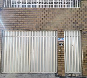 two metal garages on the side of a brick building at Suíte Central Confort in Juazeiro do Norte