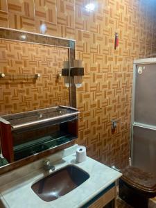 a bathroom with a sink and a mirror and a toilet at Suíte Central Confort in Juazeiro do Norte