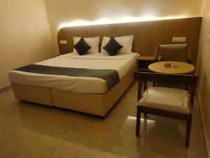a bed in a room with a table and a bed sidx sidx sidx at Hotel Meridian Blue in Warangal