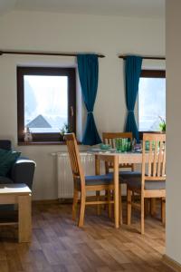 a dining room with a table and chairs and two windows at Penzion U Lípy in Velké Karlovice