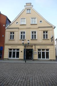 een groot gebouw aan een geplaveide straat bij Hotel Am Dom in Greifswald