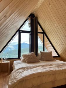 a bed in a room with a large window at Khoj The Lake Trail in Nārkanda