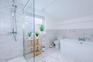 a white bathroom with a tub and a toilet and a sink at Stylish 3-Bed City Centre Home in Chester by 53 Degrees Property, Ideal for Groups, Private Parking! in Chester +25 photos