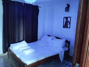 a bedroom with a bed with white sheets and pillows at Precious Homestays in Maragoli