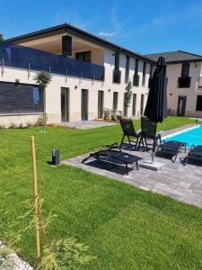 a patio with chairs and an umbrella and a pool at Pipacs 17 by HelloBalatonlelle in Balatonlelle +10 photos