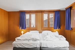two beds in a room with blue windows at Charmant appartement familiale proche de Saas-Fee in Saas-Grund +14 photos