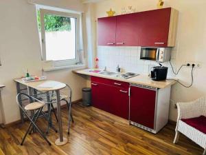 a small kitchen with red cabinets and a table at Nordsee Apartment in Hagen