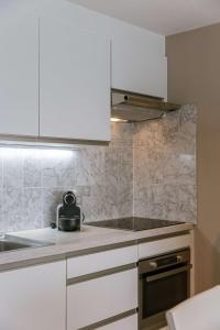 - une cuisine avec des placards blancs et une bouilloire sur le comptoir dans l'établissement Cozy studio with harbor view in Blankenberge, à Blankenberge