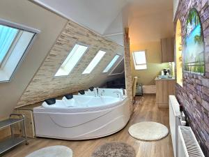 a bathroom with a large white tub and skylights at Apartman Siesta Bük - Bükfürdő in Bük