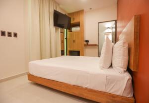 a bedroom with a bed with white sheets and a television at Mandarina's House Hotel in Tuxtla Gutiérrez