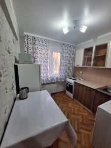 een keuken met een witte tafel en een koelkast bij квартира in Balqash +2 foto's